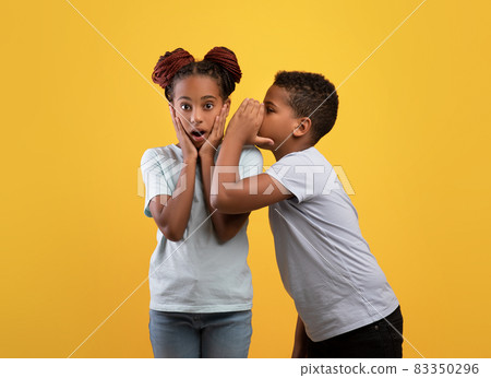 Black boy brother sharing secrets with his shocked sister 83350296
