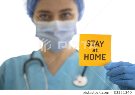 Young doctor with a mask on his face and holds a paper that says "stay at home" 83351340