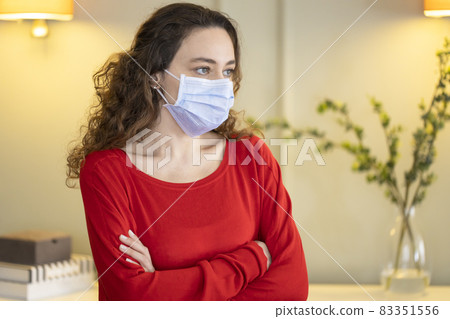 Young woman wearing a mask to protect herself against the coronavirus at home Young woman wearing a mask to protect herself against the coronavirus at home 83351556