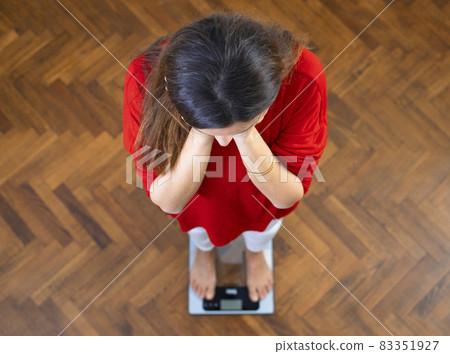 Beautiful brunette woman on scales 83351927