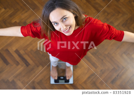 Beautiful brunette woman on scales 83351928