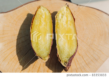 Sweet potato cut into half on wooden plate. 83353833