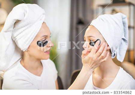Mother and her daughter using collagen patches for eyes 83354862