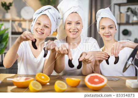 Mother with two daughters holding collagen patches in hands 83354873