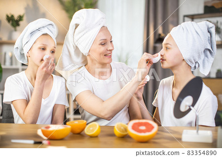 Happy mother teaching her daughters to take care of skin Happy mother teaching her daughters to take care of skin 83354890