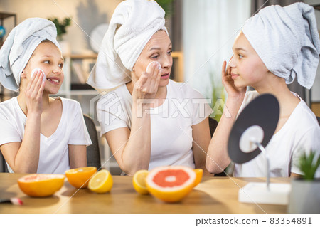 Happy mother teaching her daughters to take care of skin Happy mother teaching her daughters to take care of skin 83354891