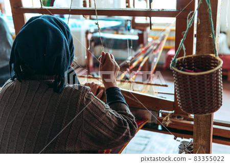 Woman weaving a fabric with on traditional pedal loom 83355022