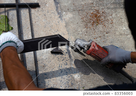 Close up, A man working with angle grinder. Iron gate repair 83356003