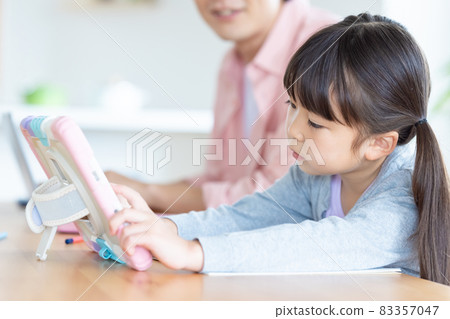Family A girl studying with a tablet with a father who works in the living room Family A girl studying with a tablet with a father who works in the living room 83357047