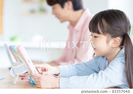 Family A girl studying with a tablet with a father who works in the living room Family A girl studying with a tablet with a father who works in the living room 83357048