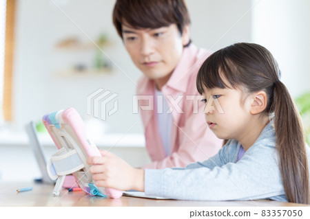 Family A girl studying with a tablet with a father who works in the living room Family A girl studying with a tablet with a father who works in the living room 83357050