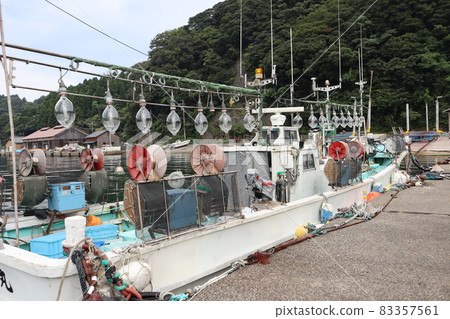 Scenery of squid fishing boats, harbors where boats stop, work huts, mountains and cloudy sky seen from the concrete coast 83357561