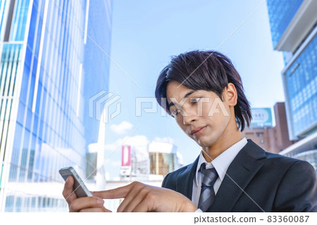 Shibuya, a businessman with a troubled expression who operates a smartphone Shibuya, a businessman with a troubled expression who operates a smartphone 83360087