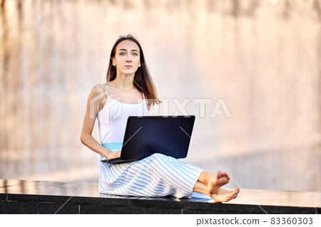 Slim woman has e-learning using laptop outdoors. Slim woman has e-learning using laptop outdoors. 83360303