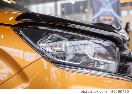 Orange car headlights. Exterior detail. Close up detail on one of the LED headlights modern car. 83360780