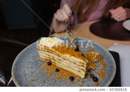Slice of layered honey cake russian Medovik decorated with mint and almonds on white plate. 83360816