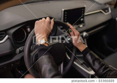 woman's hands holding on to the wheel of a new car in the showroom. 83360889