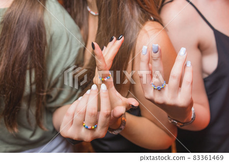 close-up view of a man's hand showing a ring with an LGBT rainbow wristband. 83361469