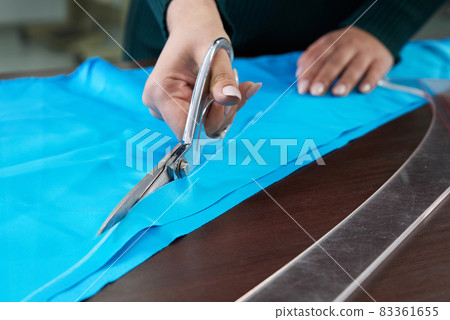 Dressmaker cutting blue fabric in tailor studio, atelier shop 83361655