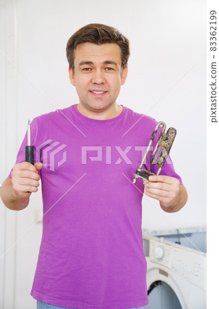 repairman of washing machine holds old tubular electric heater and screwdriver repairman of washing machine holds old tubular electric heater and screwdriver 83362199
