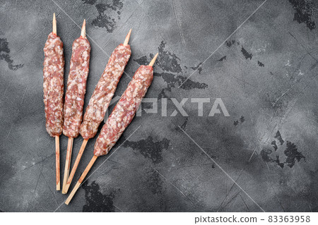 Raw mutton kebab shish skewers, on gray stone table background, top view flat lay, with copy space for text 83363958