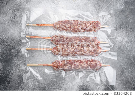 Turkish uncooked shish minced meat kofta in vacuum pack, on gray stone table background, top view flat lay 83364208
