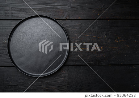 Empty black plate, on black wooden table background Empty black plate, on black wooden table background 83364258
