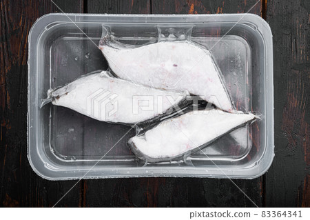 Halibut fish frozen steak pack, on old dark wooden table background, top view flat lay 83364341