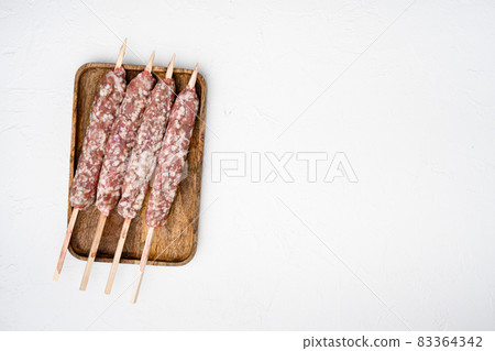 Raw Lula kebab on skewers, on white stone table background, top view flat lay, with copy space for text Raw Lula kebab on skewers, on white stone table background, top view flat lay, with copy space for text 83364342