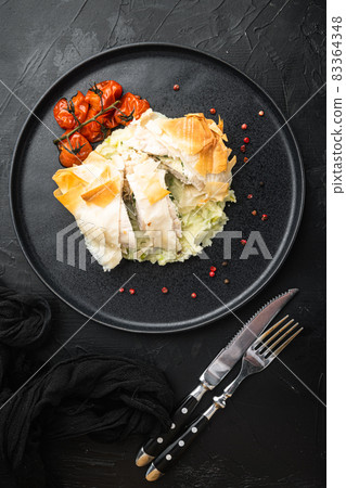 Freshly cooked Chicken Kiev oozing garlic and parsley butter, with baked cherry tomatoes, mashed potatoes, on black stone background, top view flat lay Freshly cooked Chicken Kiev oozing garlic and parsley butter, with baked cherry tomatoes, mashed potatoes, on black stone background, top view flat lay 83364348
