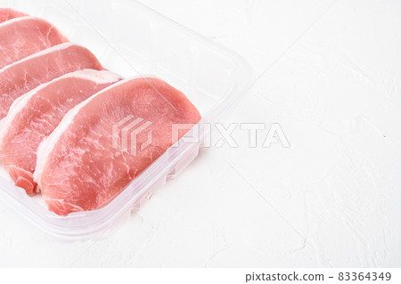 Pork meat. Fresh pork steaks, in plastic pack container, on white stone table background, with copy space for text Pork meat. Fresh pork steaks, in plastic pack container, on white stone table background, with copy space for text 83364349