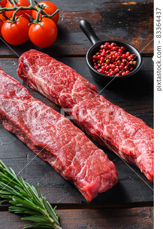 Raw denver steak or organic top blade with herbs on old wooden planks surface side view vertical close up 83364437