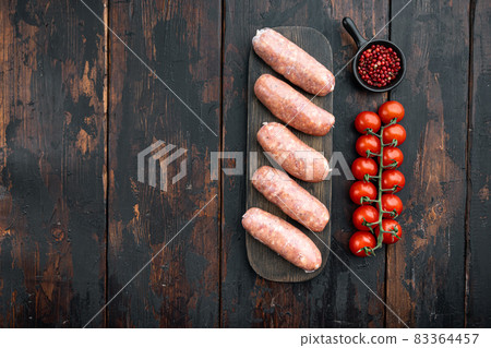 Homemade raw pork sausages with space for text, on old dark wooden background 83364457