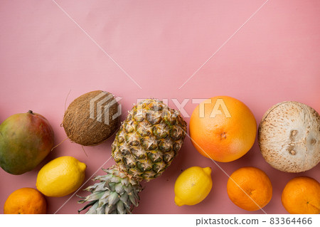 Ripe juicy fresh tropical fruits, on pink textured summer background, top view flat lay, with copy space for text Ripe juicy fresh tropical fruits, on pink textured summer background, top view flat lay, with copy space for text 83364466