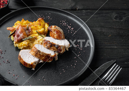 Roasted pork loin with mash potatoe gratin, sage and prosciutto, on plate dish, on black wooden table background , with copyspace and space for text Roasted pork loin with mash potatoe gratin, sage and prosciutto, on plate dish, on black wooden table background , with copyspace and space for text 83364467