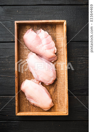 Fresh Raw sliced cut chicken breast fillet steaks, in wooden box, on black wooden table background, top view flat lay Fresh Raw sliced cut chicken breast fillet steaks, in wooden box, on black wooden table background, top view flat lay 83364469