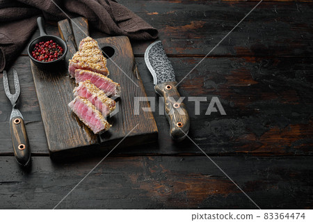 Homemade Cut Grilled Sesame Tuna steak, on wooden serving board, on old dark wooden table background , with copyspace and space for text Homemade Cut Grilled Sesame Tuna steak, on wooden serving board, on old dark wooden table background , with copyspace and space for text 83364474