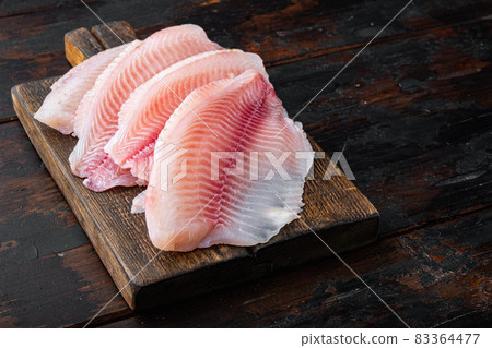 Tilapia fish skinless meat, on old wooden table Tilapia fish skinless meat, on old wooden table 83364477