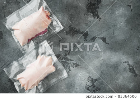 Vacuum packed raw duck breast, on gray stone background, top view flat lay, with copyspace  and space for text 83364506