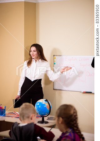 Primary school kids sitting at school class and listening to a teacher at lesson. 83365910