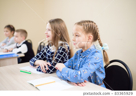 Primary school children work together in class. 83365929