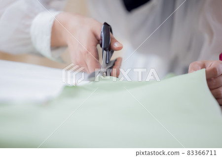 Fashion college student, a woman's hand cutting cloth with cutting scissors Fashion college student, a woman's hand cutting cloth with cutting scissors 83366711
