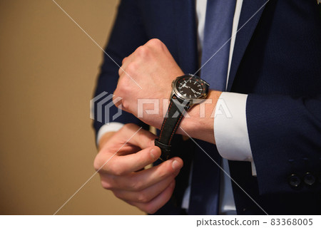 Elegant businessman dressed clock before meeting with partners. Elegant businessman dressed clock before meeting with partners. 83368005