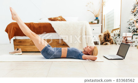 Woman training abdominal muscles lifting legs up lying on floor Woman training abdominal muscles lifting legs up lying on floor 83368562