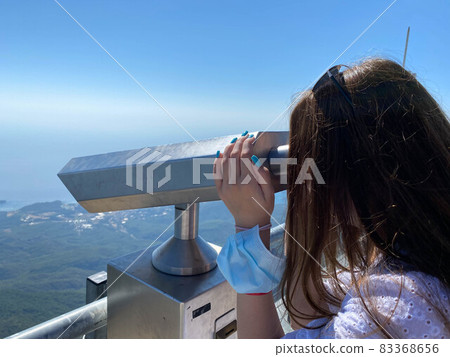 The girl looks at the mountains and the sky from a large fortress wall in the city of Antalya in Turkey. It uses a monocular, a telescope, binoculars and this service is paid 83368656