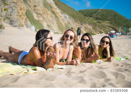 Smiling female friends sunbathing Smiling female friends sunbathing 83369306