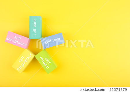 Mental health formula concept. Self acceptance, self care, self respect and self forgiveness written on flower from multicolored rectangles on yellow background with copy space Mental health formula concept. Self acceptance, self care, self respect and self forgiveness written on flower from multicolored rectangles on yellow background with copy space 83371879