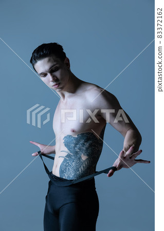Close-up young muscled man, male ballet dancer posing isolated on old navy studio background. Art, motion, inspiration concept. Close-up young muscled man, male ballet dancer posing isolated on old navy studio background. Art, motion, inspiration concept. 83372162