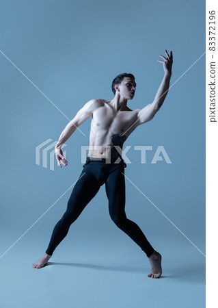 Young and graceful male ballet dancer isolated on old navy studio background. Art, motion, action, flexibility, inspiration concept. 83372196