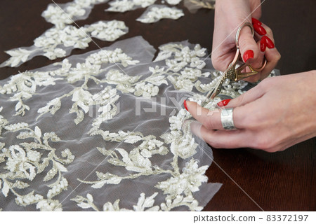 selective focus of seamstress cutting lace with scissors in atelier studio selective focus of seamstress cutting lace with scissors in atelier studio 83372197